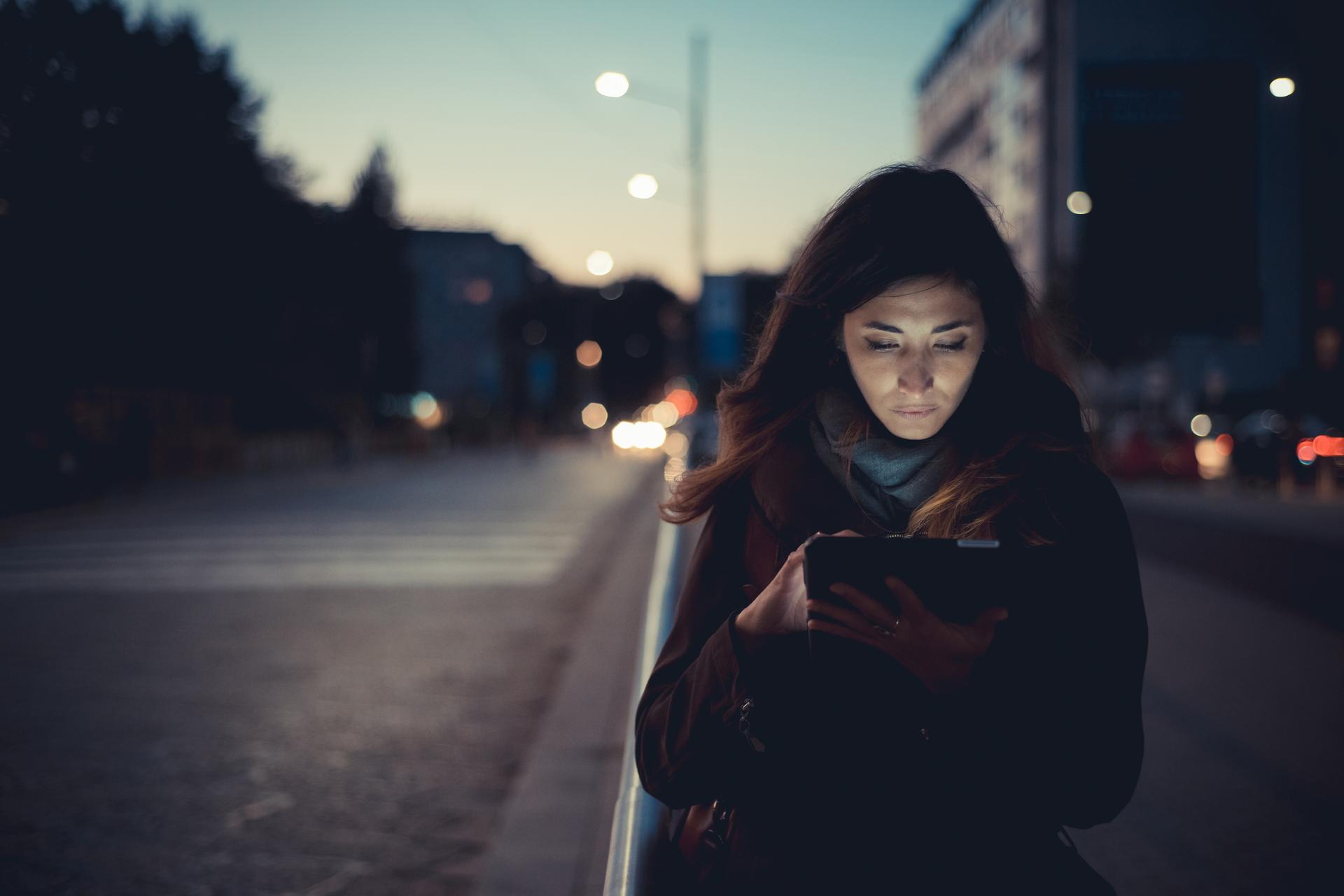 94552 Mid adult woman using digital tablet on street at dusk