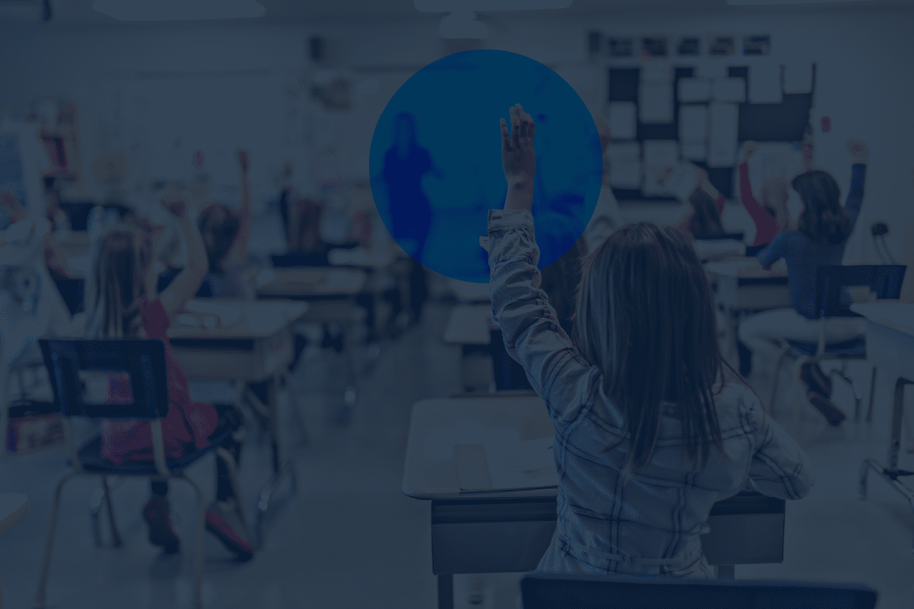 A classroom of primary school children sits at individual desks with several pupils raising their hands to answer a question while a teacher stands at the front. A dark blue overlay with a subtle circular design covers the image, creating space for website headings and page content.