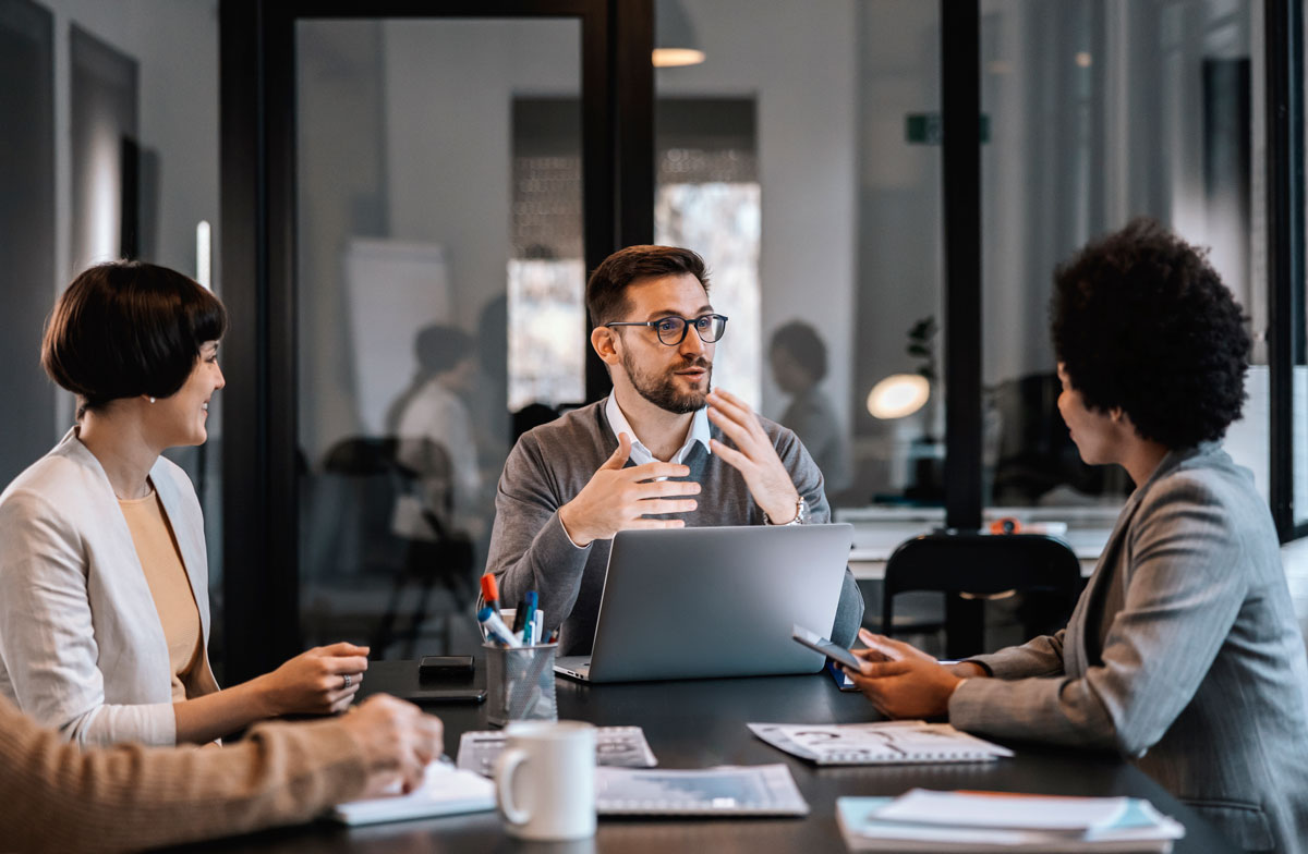 Several people sit at a meeting table and talk