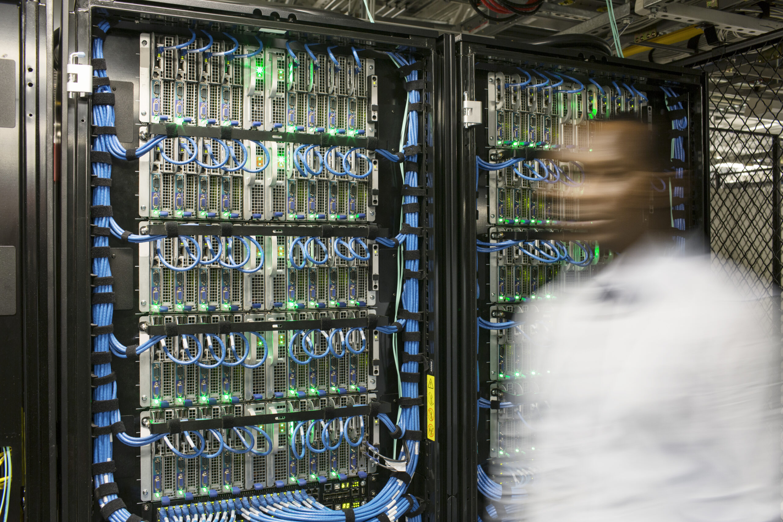 Black man technician doing diagnostic tests on computer servers in server farm.