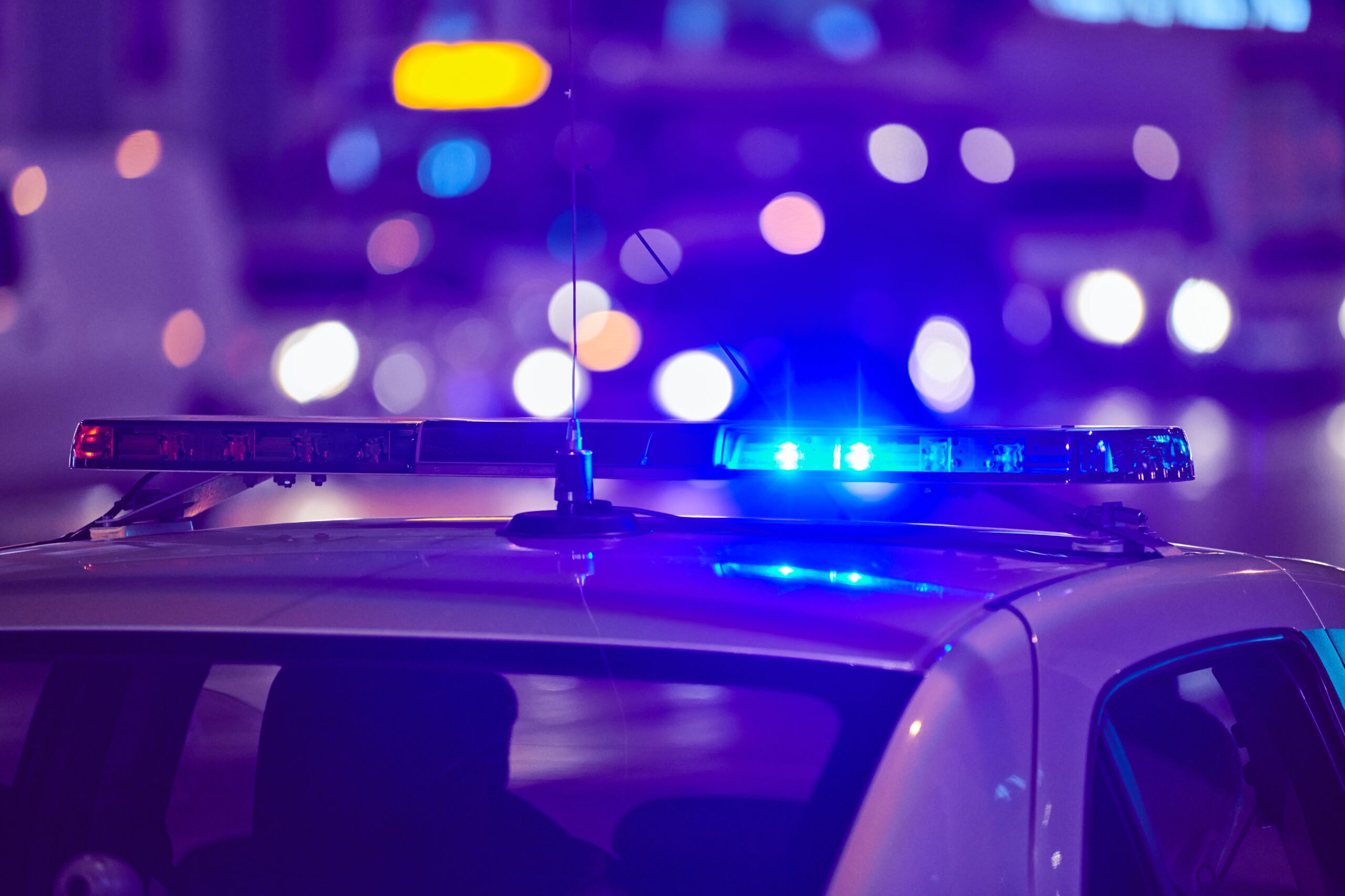 Police car with flashing lights at night representing Clare’s Law and data insights powered by Databricks Genie