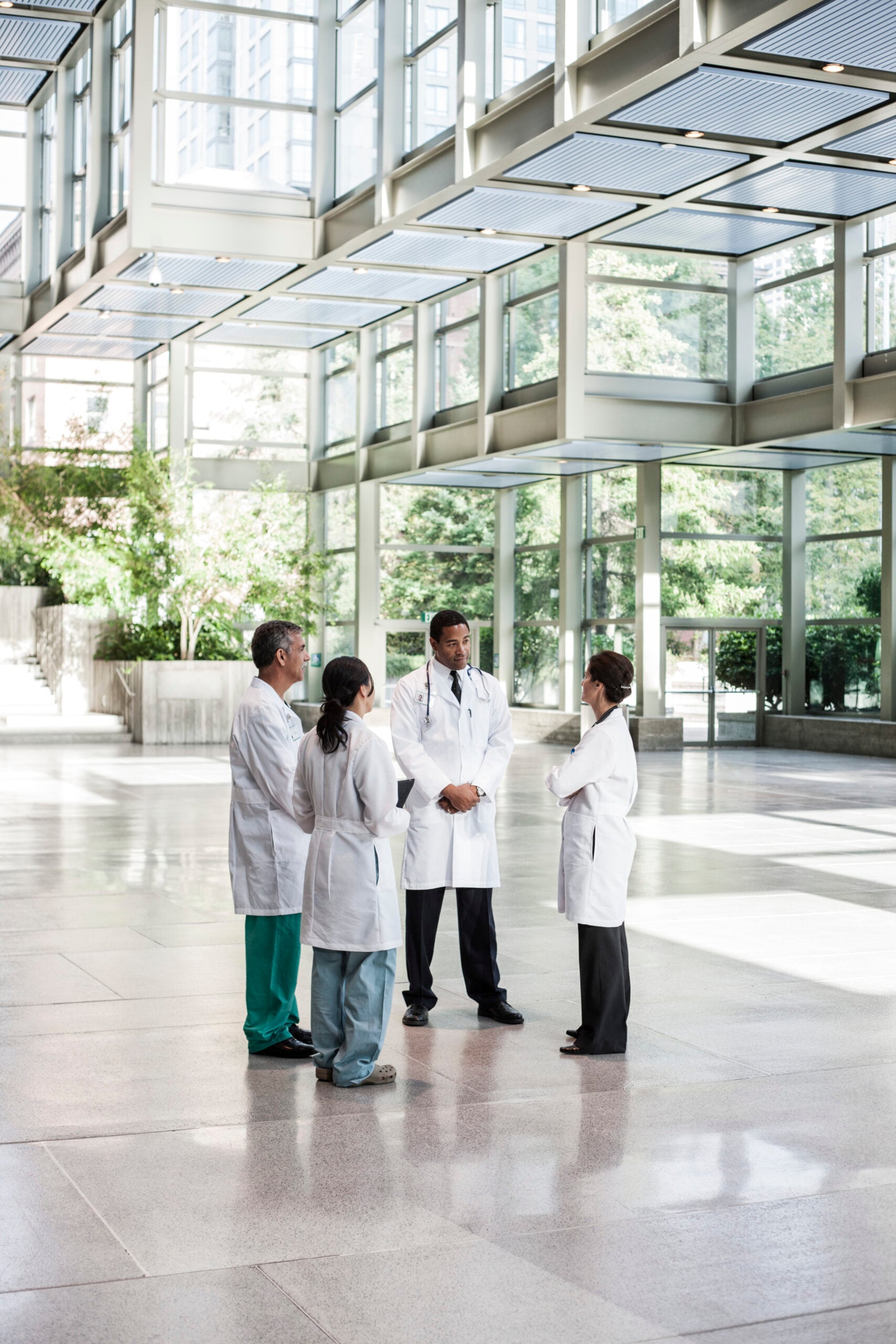 Group of doctors discussing in hospital atrium NHS Federated Data Platform collaboration
