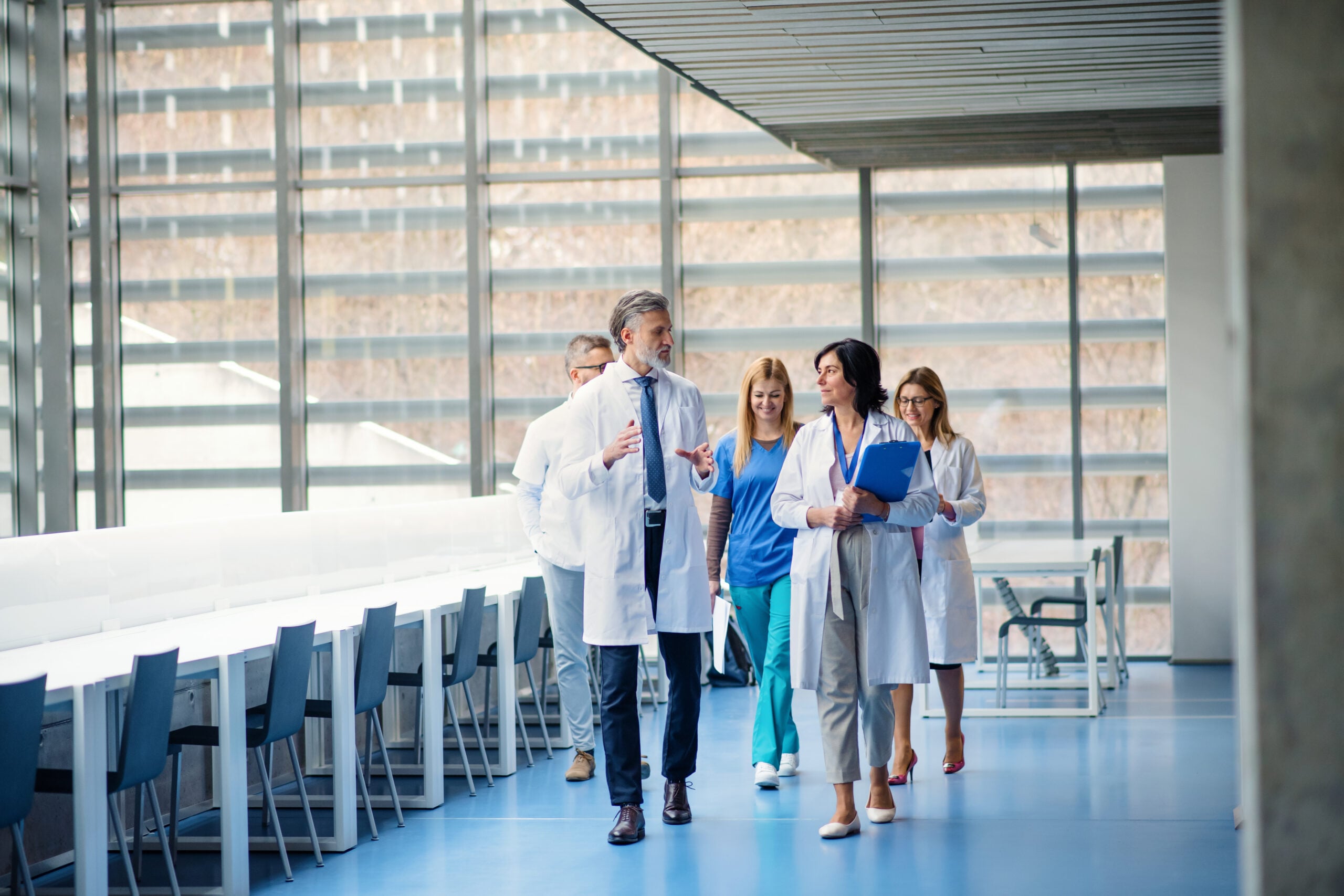 Doctor and nurses walking in hospital corridor reviewing patient data NHS Federated Data Platform