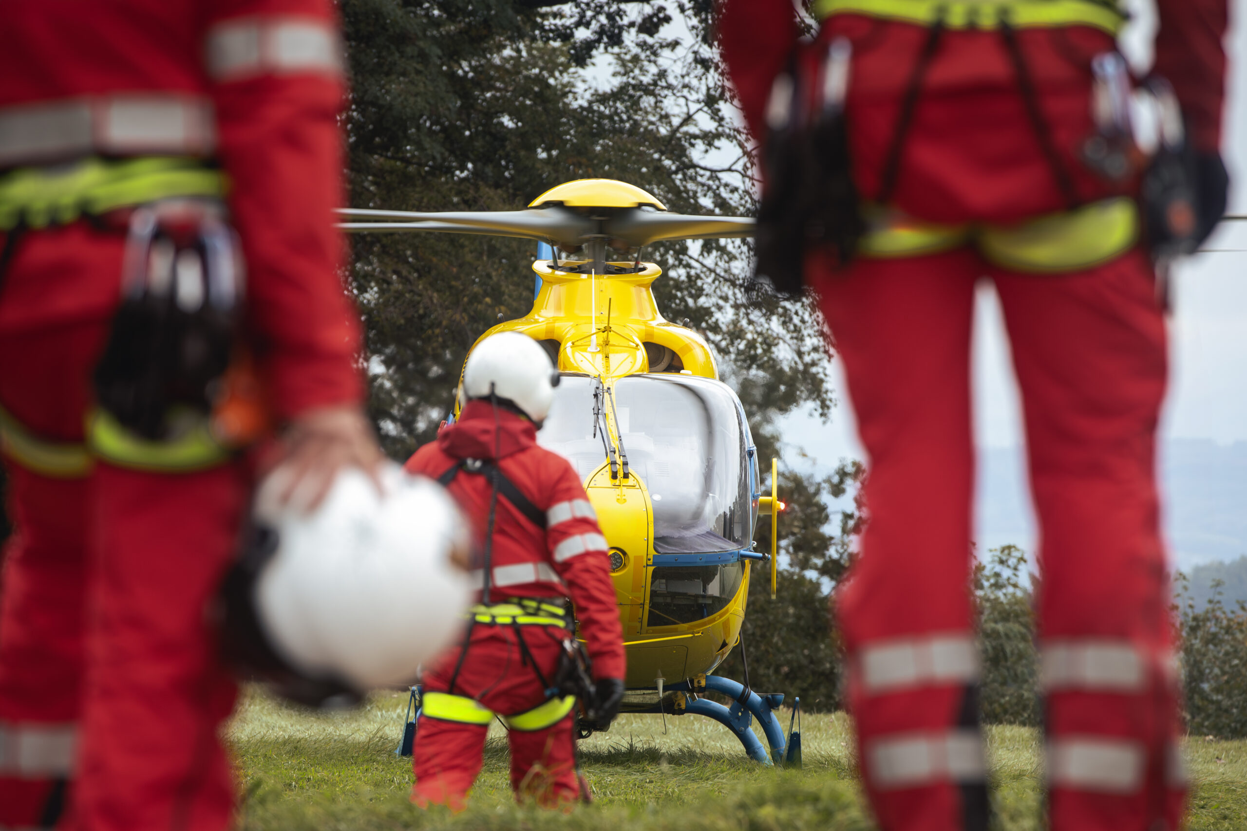 Rear view of team of emergency medical service. Doctor and paramedics with safety harness and climbing equipment running to helicopter. Themes rescue, help and hope.